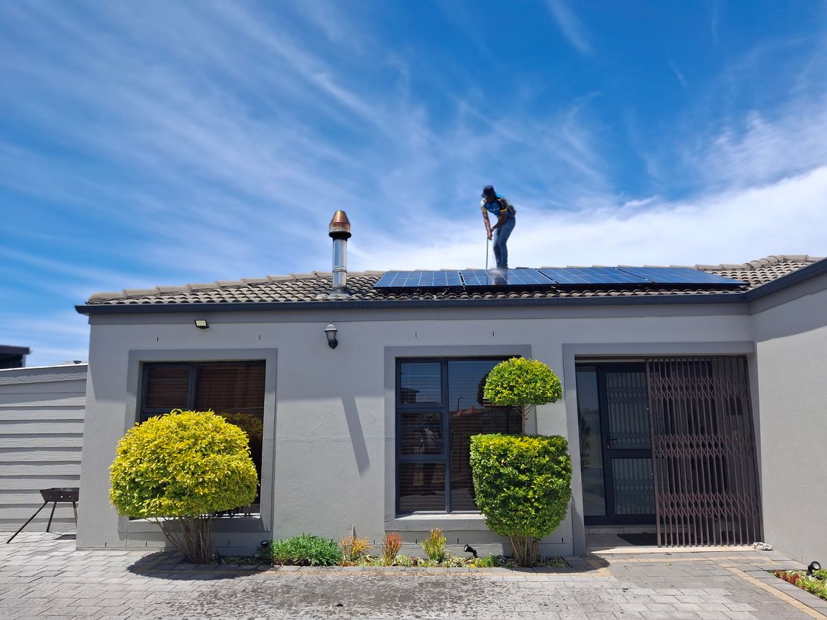 住宅の屋根に設置された太陽光パネルと作業員の参考写真